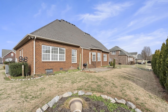 rear view of house with brick siding, a yard, a patio, and roof with shingles