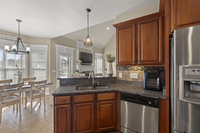 kitchen featuring light tile patterned flooring, a sink, appliances with stainless steel finishes, backsplash, and dark stone countertops