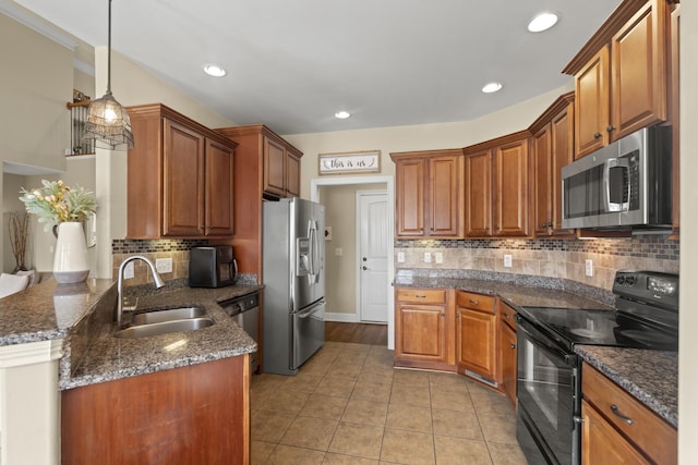 kitchen featuring brown cabinets, decorative light fixtures, a peninsula, stainless steel appliances, and a sink