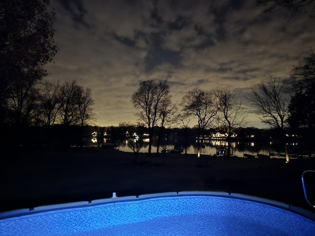 pool at dusk with a water view and an outdoor pool