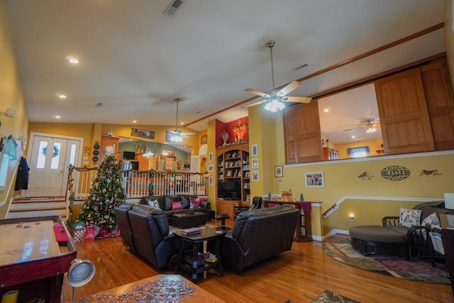 living room featuring vaulted ceiling, visible vents, light wood-style flooring, and a ceiling fan