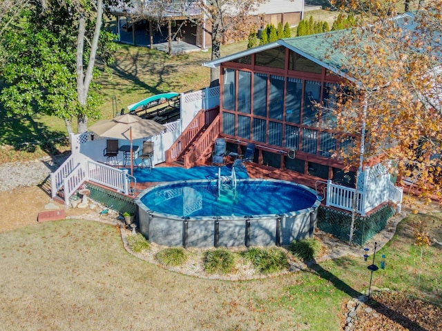 exterior space featuring a lawn, a fenced in pool, a sunroom, stairway, and a deck