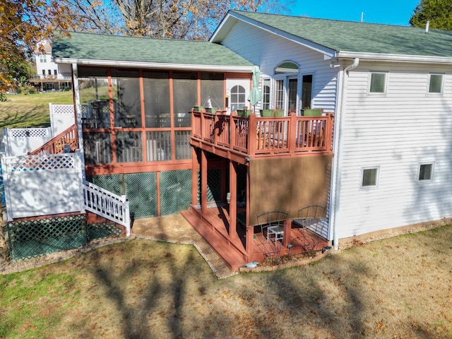 back of property featuring a yard, a shingled roof, a wooden deck, and a sunroom