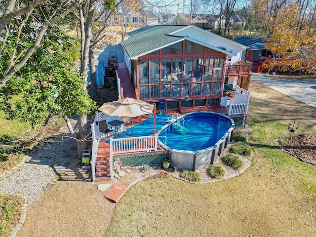 exterior space featuring a yard, stairway, a sunroom, an outdoor pool, and a wooden deck