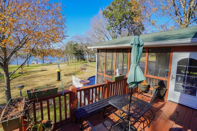 wooden terrace featuring a yard, outdoor dining area, and a sunroom