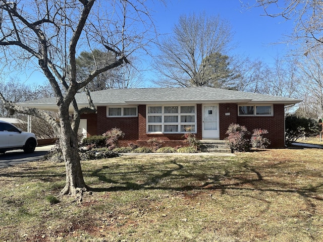 single story home with a front lawn, an attached carport, and brick siding