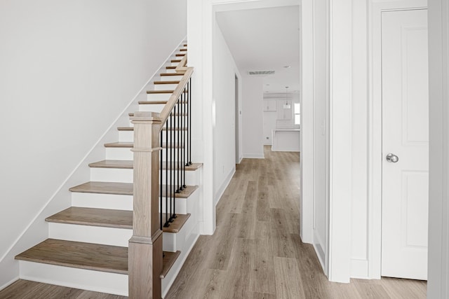 stairs featuring wood finished floors, visible vents, and baseboards