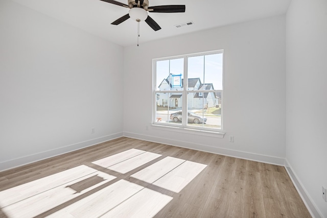 unfurnished room with a ceiling fan, baseboards, visible vents, and light wood finished floors