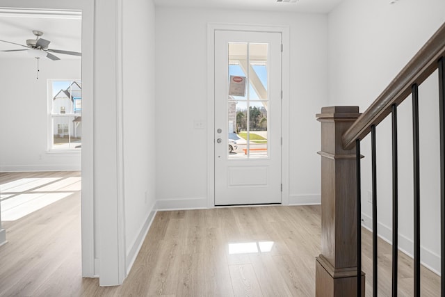 entryway with plenty of natural light, stairs, baseboards, and wood finished floors