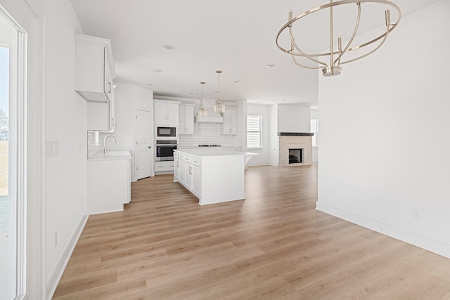 kitchen featuring black microwave, a sink, stainless steel oven, open floor plan, and decorative backsplash