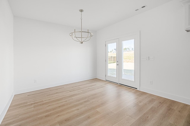 spare room featuring a chandelier, baseboards, visible vents, and light wood-style floors