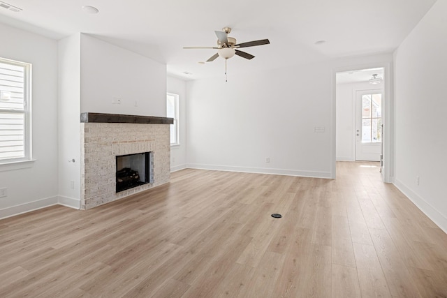 unfurnished living room with light wood-type flooring, ceiling fan, a fireplace, and visible vents