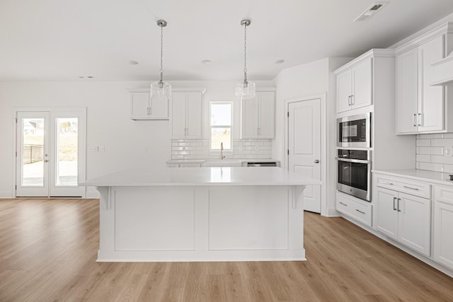 kitchen with a center island, light wood-style flooring, stainless steel oven, a sink, and built in microwave