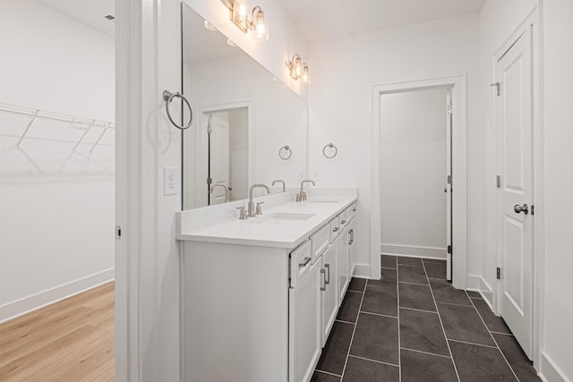 bathroom with a sink, a spacious closet, baseboards, and double vanity