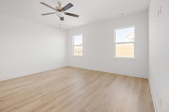 empty room featuring baseboards, visible vents, a ceiling fan, and light wood-style floors