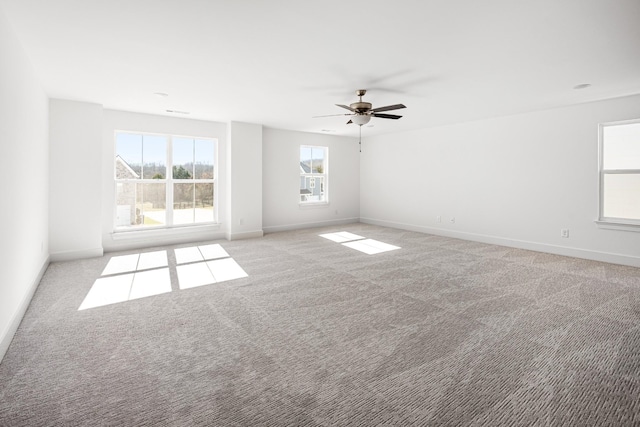 empty room with baseboards, a ceiling fan, and light colored carpet