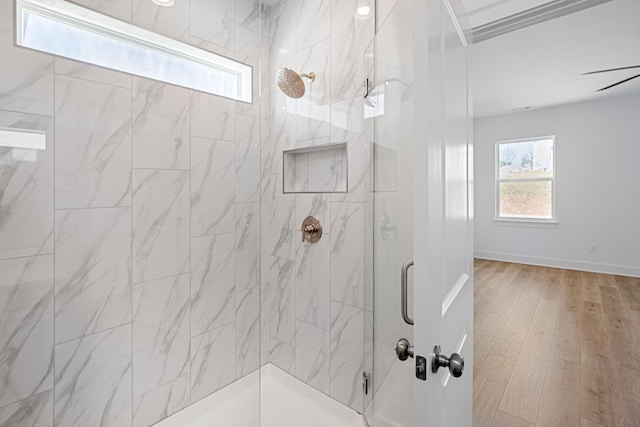 bathroom featuring wood finished floors, walk in shower, and baseboards