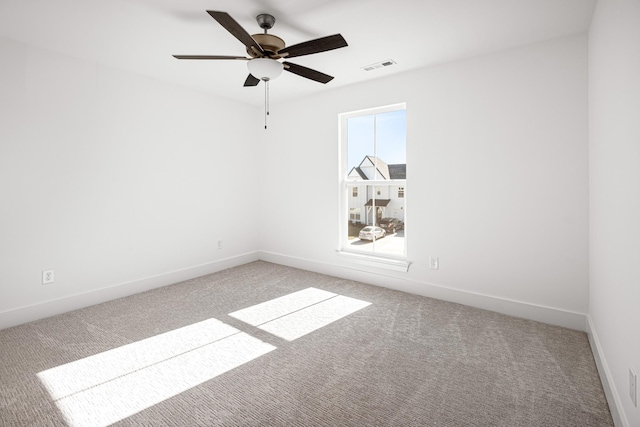 carpeted empty room with ceiling fan, visible vents, and baseboards