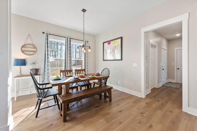 dining space featuring a notable chandelier, light wood-type flooring, and baseboards