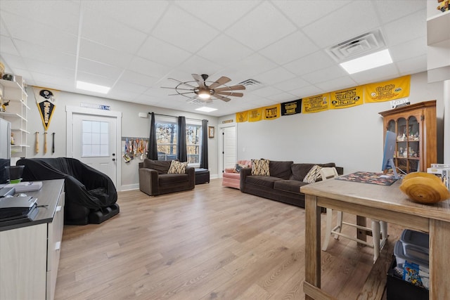 living room featuring light wood-type flooring, visible vents, ceiling fan, and a drop ceiling