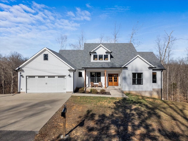 modern inspired farmhouse with a garage, covered porch, a shingled roof, driveway, and board and batten siding