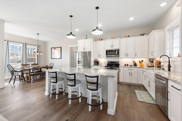 kitchen featuring appliances with stainless steel finishes, dark wood-type flooring, a sink, and decorative backsplash