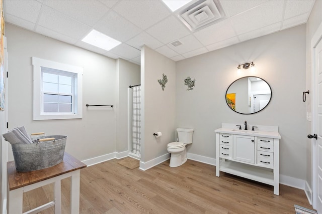 bathroom featuring a paneled ceiling, wood finished floors, toilet, and baseboards