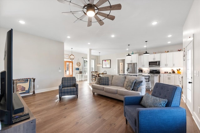 living area featuring baseboards, ceiling fan, wood finished floors, and recessed lighting