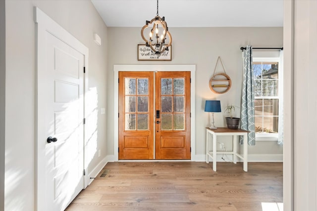 doorway with light wood-type flooring, french doors, a notable chandelier, and baseboards