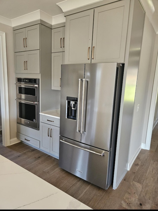 kitchen featuring stainless steel appliances, gray cabinets, dark wood finished floors, and baseboards