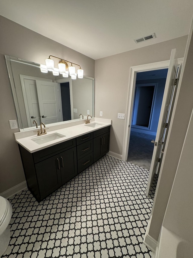 full bath with visible vents, a sink, baseboards, and double vanity