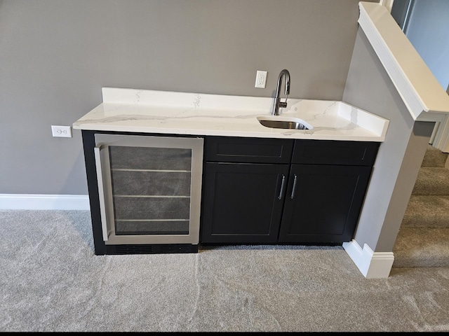 bar with light colored carpet, stairway, a sink, beverage cooler, and baseboards