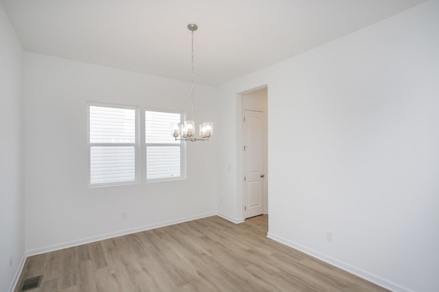 empty room featuring light wood-type flooring, baseboards, visible vents, and a chandelier