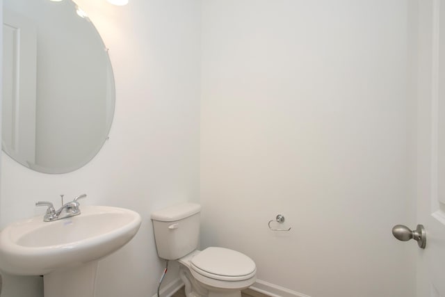 bathroom featuring baseboards, a sink, and toilet