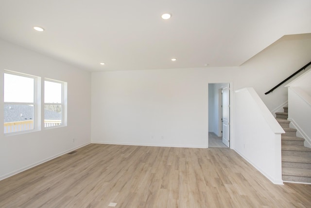 unfurnished living room featuring light wood-style flooring, stairway, baseboards, and recessed lighting