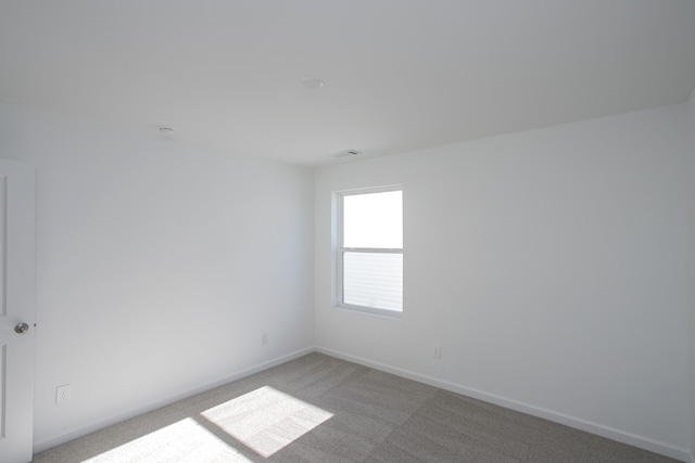 unfurnished room featuring visible vents, baseboards, and light colored carpet