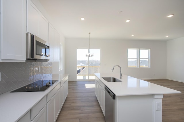 kitchen featuring stainless steel appliances, decorative backsplash, a sink, and light wood-style floors