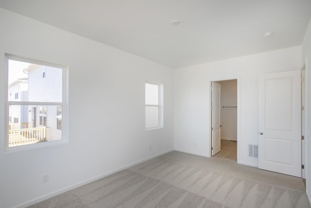 unfurnished bedroom featuring light colored carpet, visible vents, and baseboards