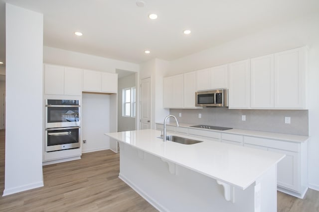 kitchen with stainless steel appliances, backsplash, a sink, and white cabinets