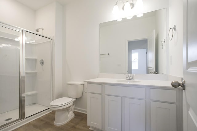 bathroom with toilet, a stall shower, wood finished floors, and vanity