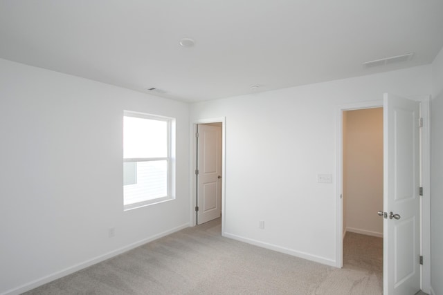 empty room with light carpet, visible vents, and baseboards