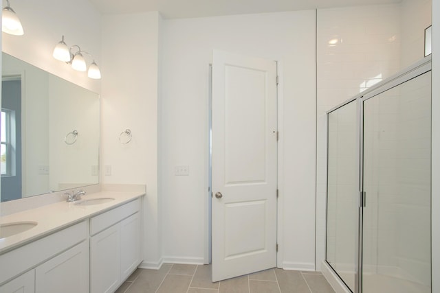 full bath featuring double vanity, a stall shower, a sink, and tile patterned floors