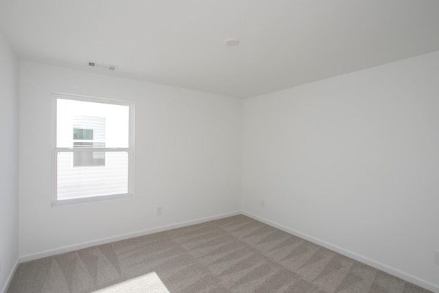 unfurnished room with light carpet, visible vents, and baseboards