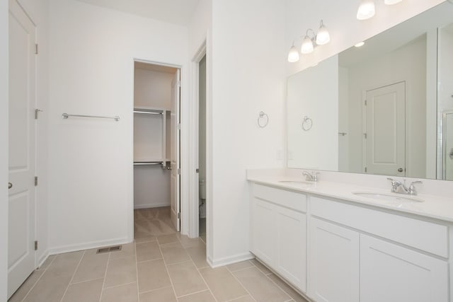 full bath with double vanity, tile patterned flooring, baseboards, and a sink