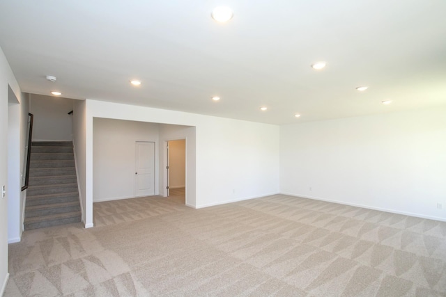 empty room with recessed lighting, light carpet, stairway, and baseboards