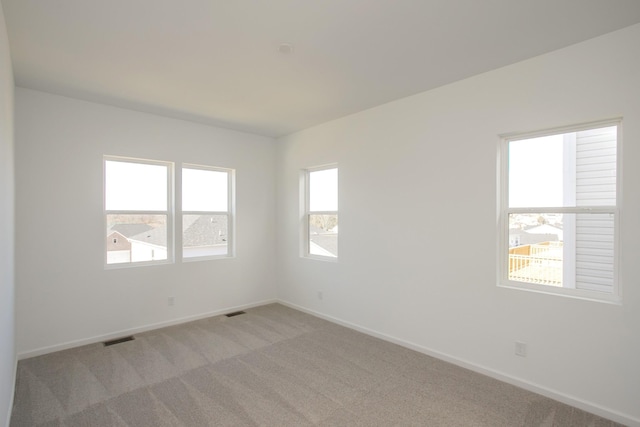 spare room with light carpet, visible vents, and baseboards