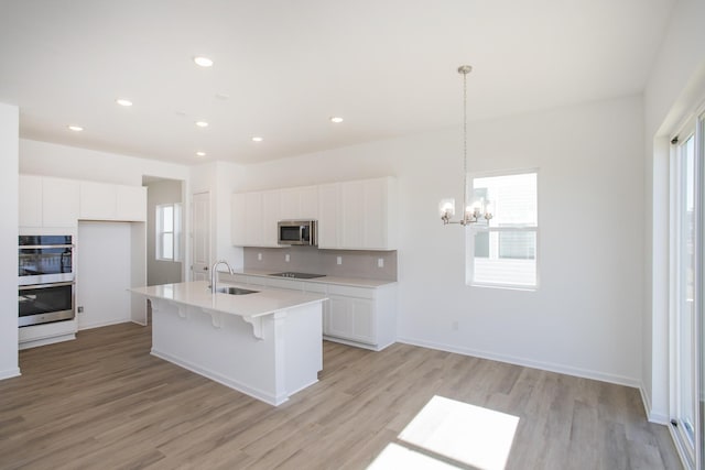 kitchen with light wood-style floors, white cabinetry, appliances with stainless steel finishes, and a sink