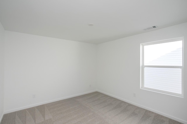 spare room with light carpet, visible vents, and baseboards