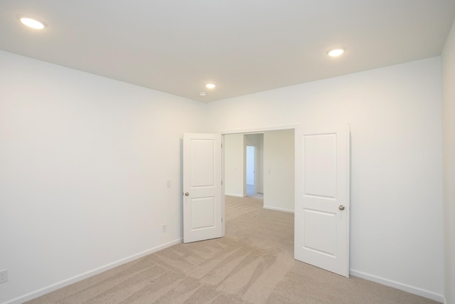 unfurnished room with recessed lighting, light carpet, and baseboards