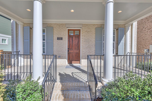 doorway to property featuring covered porch and brick siding